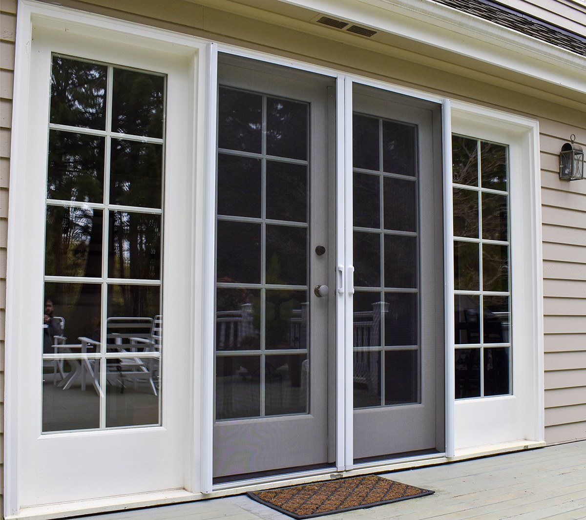 White French patio doors with retractable screen doors on a home exterior