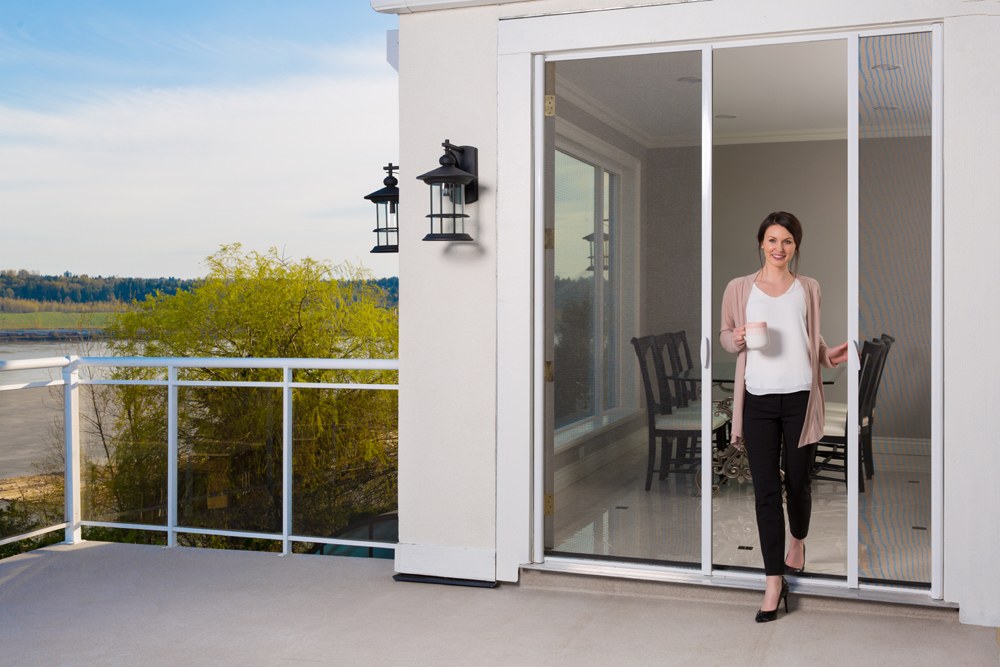 Woman stepping through a retractable screen door onto a patio